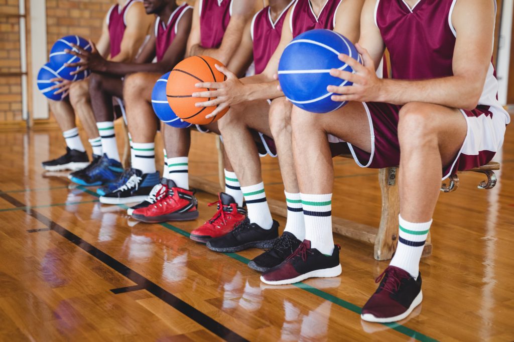 Basketball players sitting on bench with basketball — International ...